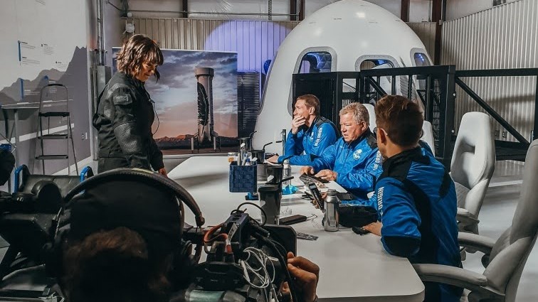 Filming a New Shepard crew at a table beside the capsule